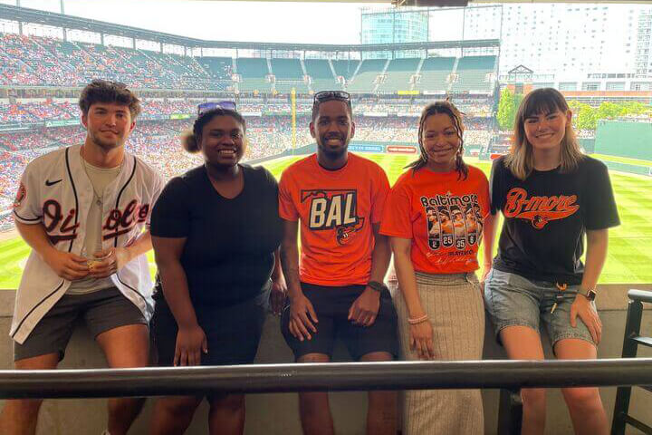 Mission's summer interns pose for a picture with the baseball field behind them