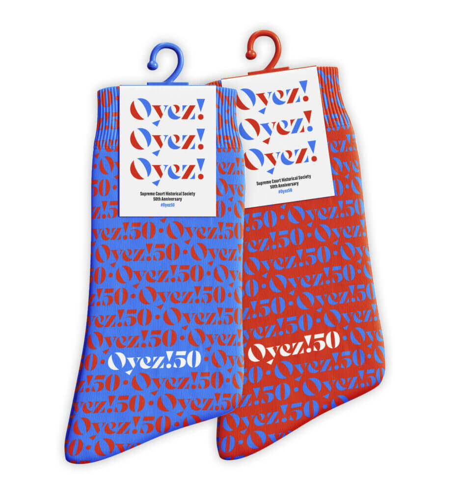 Two pairs of socks, one red and the other blue, which say “Oyez!50” repeatedly.